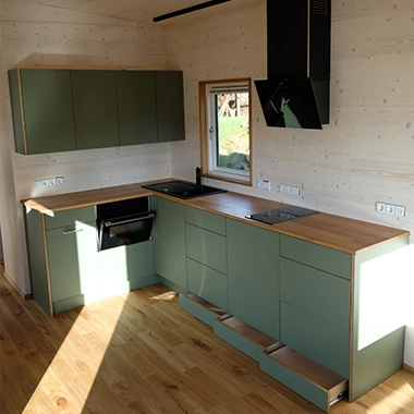 Kleinernomade-modulhouse-modell10-tinyhouse-380x380-2 Moderne Küchenzeile im Tiny House mit grünen Fronten, Holzarbeitsplatte und Einbaugeräten.