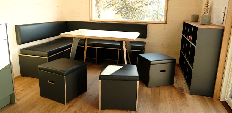 Kleinernomade-modulhouse-modell10-tinyhouse-780x380-2 Moderner Essbereich in einem Tiny House mit gepolsterter Eckbank, Holztisch, Hockern und Regal.
