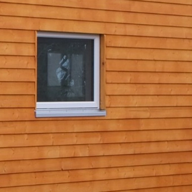 Kleinernomade-modulhouse-modell9-tinyhouse-380x380-1 Nahaufnahme eines Fensters in einer modernen Holzfassade eines Modulhauses.