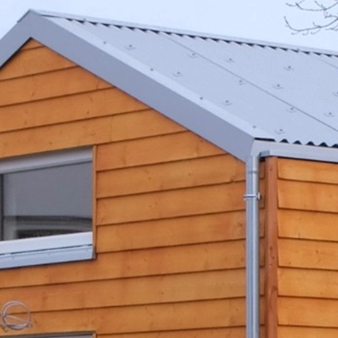 Kleinernomade-modulhouse-modell9-tinyhouse-380x380-2 Detailaufnahme des Giebels und Metalldachs eines Tiny Houses mit Holzverkleidung.