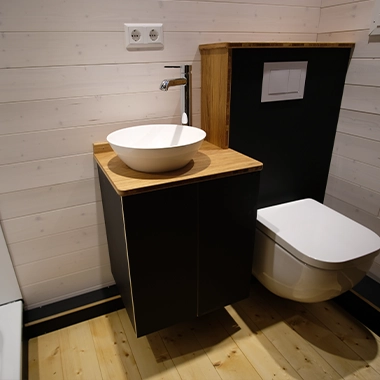 Kleinernomade-tinyhouse-modellmax72-380x380-2 Kompaktes Badezimmer mit wandhängendem WC, Aufsatzwaschbecken und Holzverkleidung.