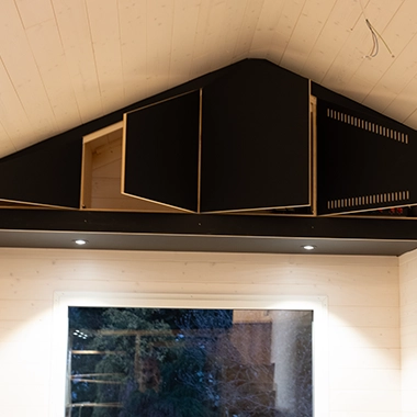 Kleinernomade-tinyhouse-modellmax72-380x380-5 Schwarze Oberschränke im Dachbereich eines Tiny Houses mit indirekter Beleuchtung.