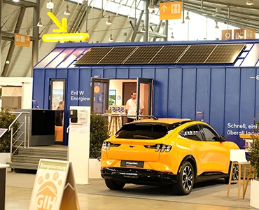 kleiner-nomade-modell-promotion-enbw Promotions Modell eines Tiny Houses in blau mit Solarmodulen in einer Messehalle.