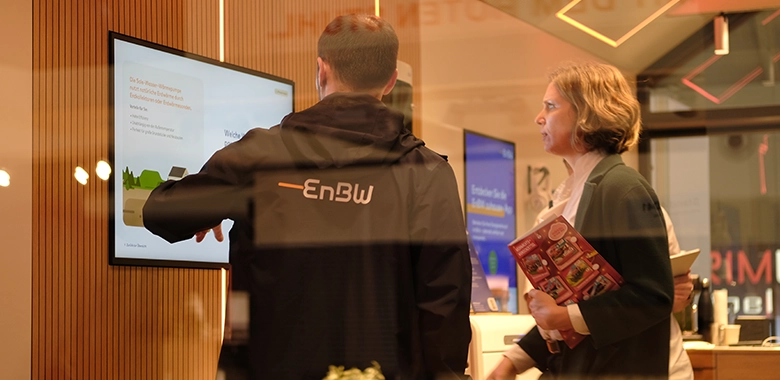kleiner-nomade-promotion-tiny-house-enew-messe5 Zwei Menschen schauen auf einem Bildschirm in einem Tiny House.