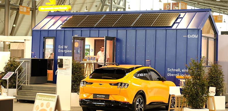 kleiner-nomade-promotion-tiny-house-enew-messe6 Promotions Modell eines Tiny Houses in blau mit Solarmodulen in einer Messehalle.
