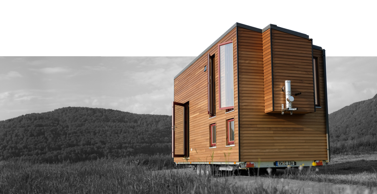 Rechteckiges, modernes Tiny House mit vertikaler Holzverkleidung, drei Fenstern und einer Glastür mit Stufen davor